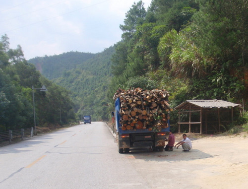 Overloaded truck with a flat tire.